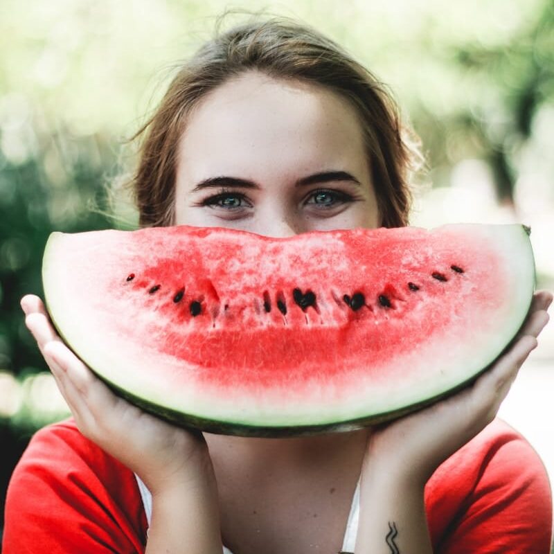 woman holding sliced watermelon