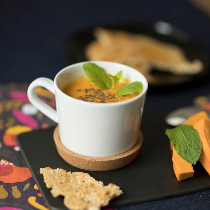 cup of carrot juice with mint on coaster